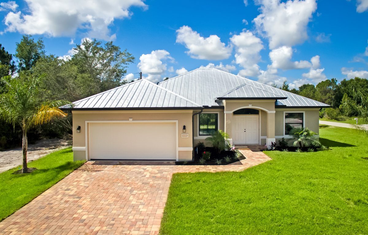 Single-story Lourdes plan custom home by Lauren Homes with metal roof, paver driveway and two-car garage on a double lot in the Buckingham area of Fort Myers