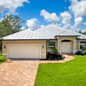 Single-story Lourdes plan custom home by Lauren Homes with metal roof, paver driveway and two-car garage on a double lot in the Buckingham area of Fort Myers