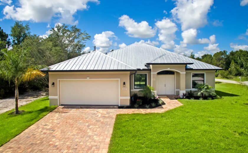 Single-story Lourdes plan custom home by Lauren Homes with metal roof, paver driveway and two-car garage on a double lot in the Buckingham area of Fort Myers
